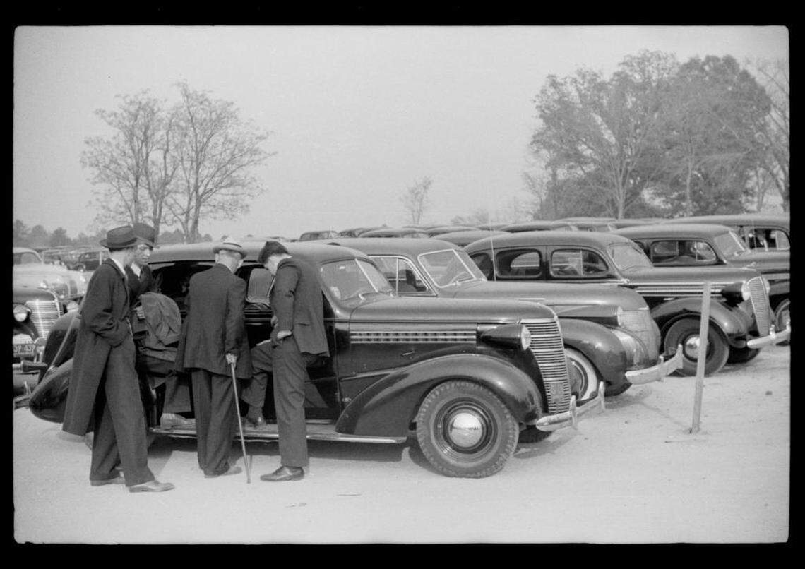 Men cluster around a car with a radio in the parking lot of the Duke-Carolina game played in Durham, NC in 1939. The game was sold out, leaving many in the parking lot.