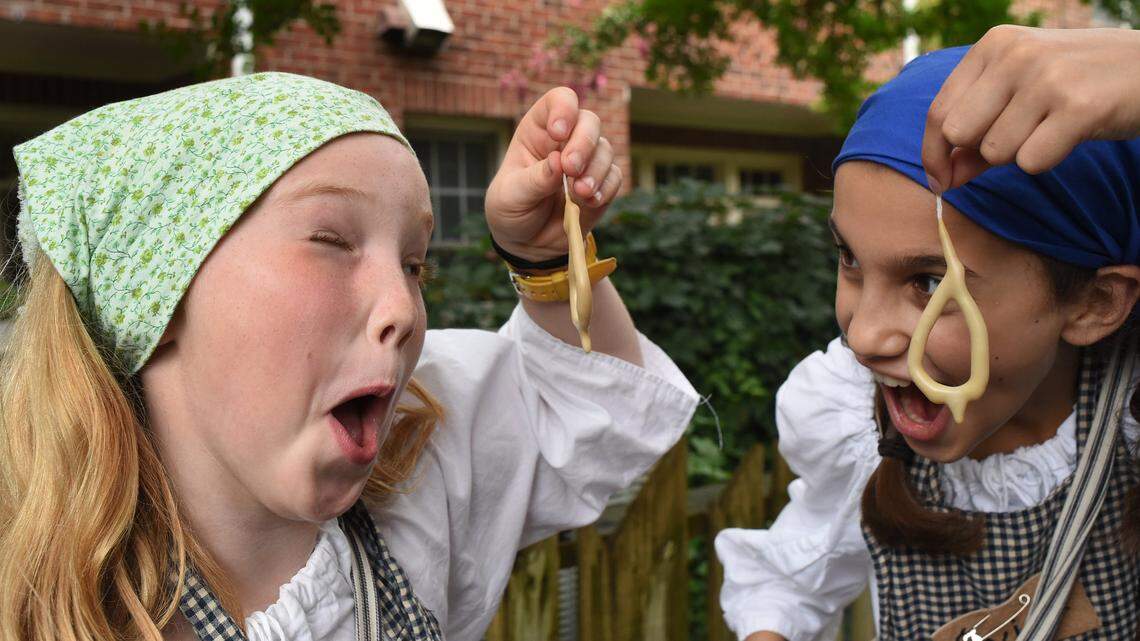 Bebe Staton (left) and Evie Georgoulias laugh as their candles look more like earrings during a candle making session at Camp Flintlock in 2017.
