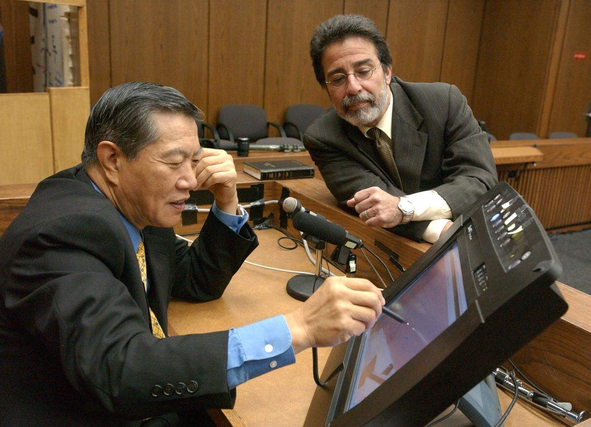 Henry C. Lee, retired head of the Connecticut Public Safety Dept. and prominent forensic scientist, left, with defense attorney David Rudolf, reviews some of the loaded evidence photos on the witness stand computer screen shortly before court began Monday morning in the Michael Peterson murder trial, September 2003.