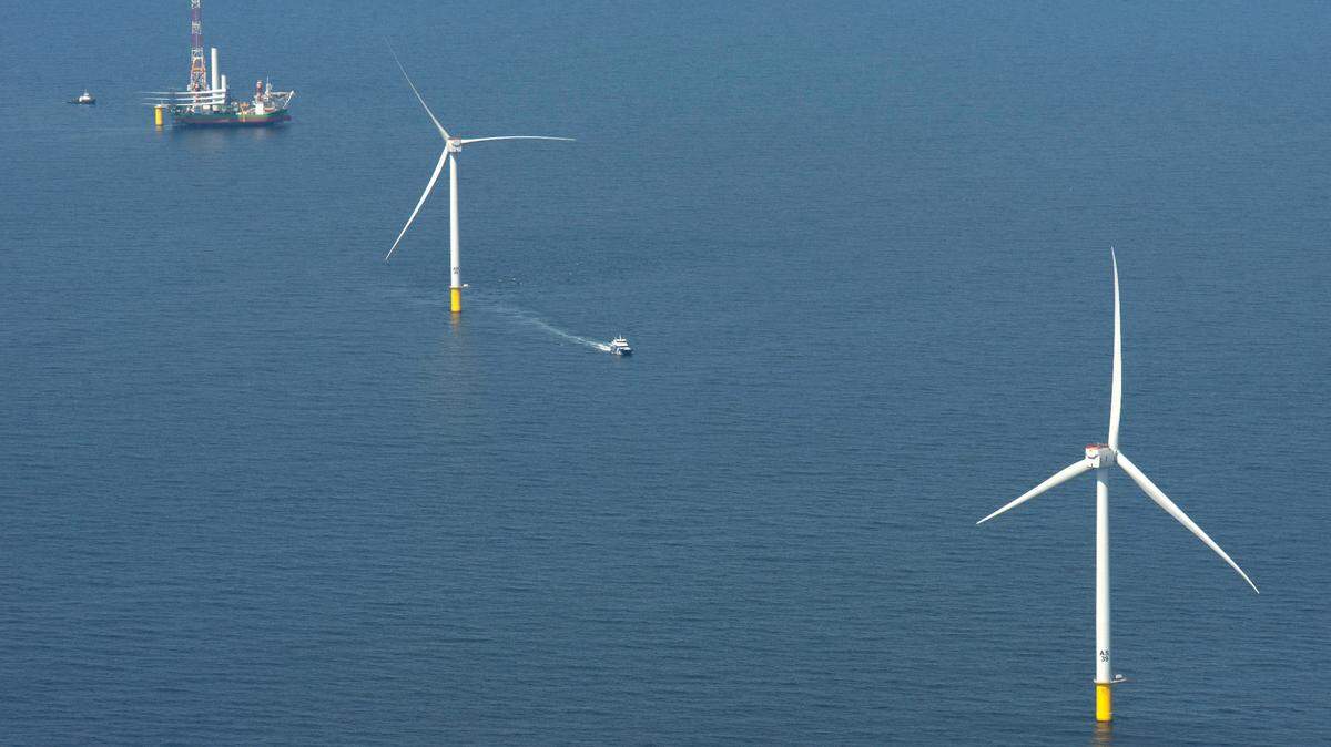 The Danish ship Sea Installer at the top of photo carries all the components for another wind turbine as it sits beside a monopile foundation for a turbine ready to install another one twelve miles south of Martha’s Vineyard at the Vineyard Wind site in April 2024.