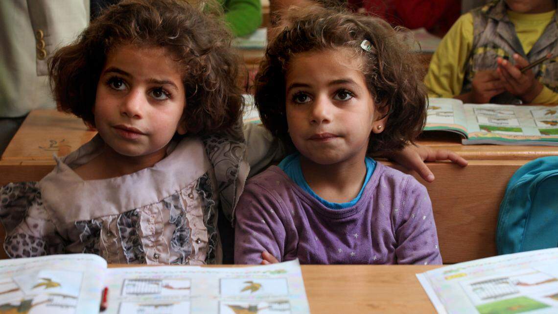 Red Hat helped UNICEF improve an online database that maps information about schools in several South American, African and Central Asian countries. In this file photo, twin sisters, who fled the fighting in Syria with their family, sit at their desks at a UNICEF school at a refugee camp.