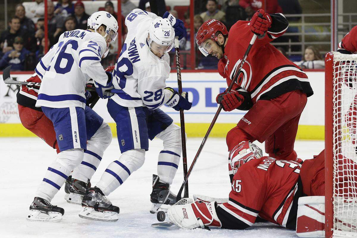 Carolina Hurricanes goalie Curtis McElhinney (35) and teammate Trevor van Riemsdyk defend the goal against Toronto Maple Leafs’ Connor Brown (28) and Par Lindholm (26), of Sweden, during the first period of an NHL hockey game in Raleigh, N.C., Wednesday, Nov. 21, 2018.