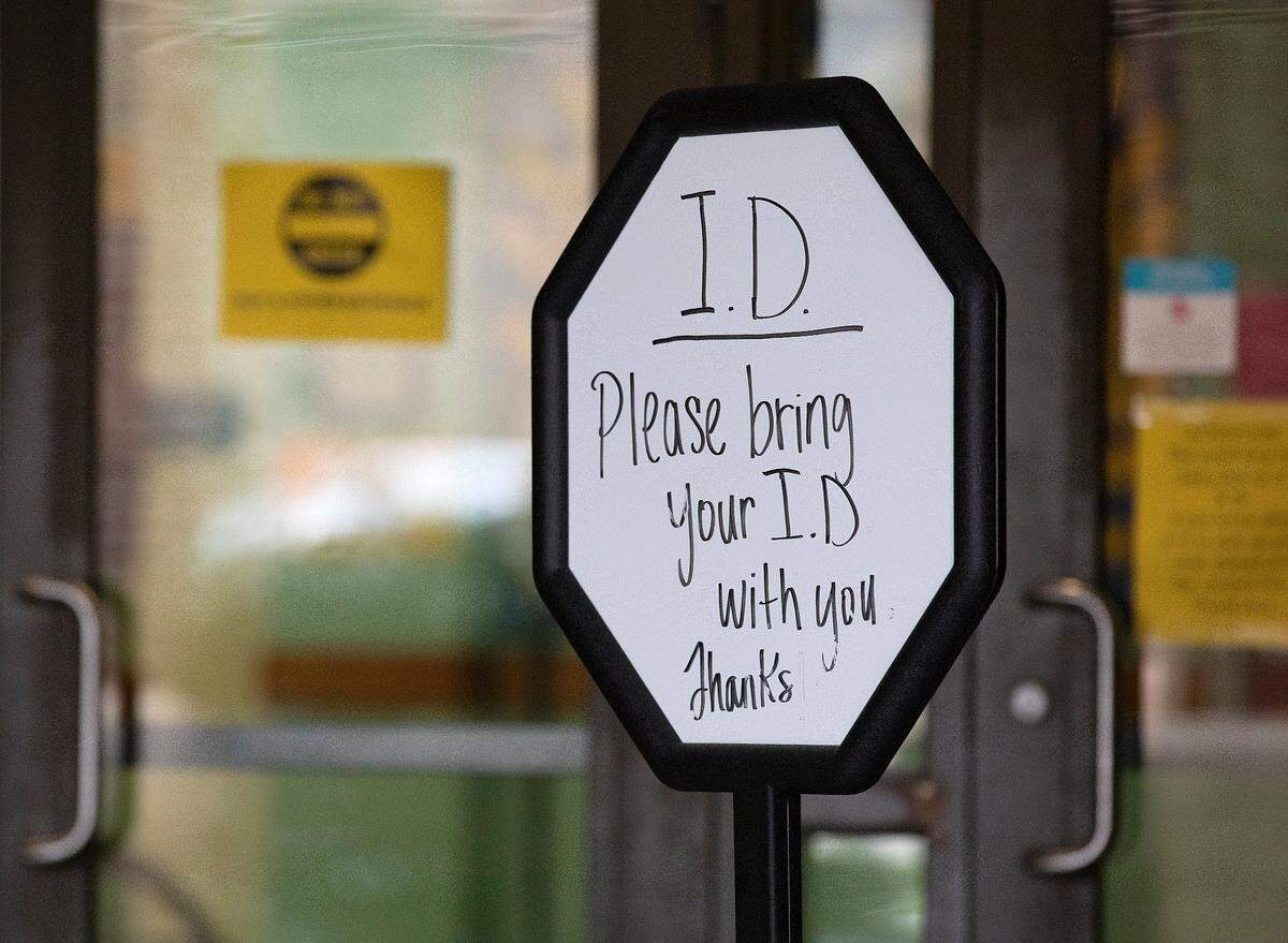 A sign alerts people to bring identification outside of a voting site at Aversboro Elementary School in Garner, N.C. on Tuesday, March 5, 2024.