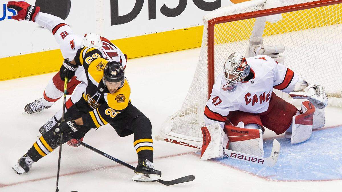 Boston Bruins’ Brad Marchand (63) protects the puck from Carolina Hurricanes’ Dougie Hamilton (19) as Hurricanes goaltender James Reimer (47) waits for the shot during the third period of an NHL Eastern Conference Stanley Cup hockey playoff game in Toronto, Thursday, Aug. 13, 2020. (Chris Young/The Canadian Press via AP)
