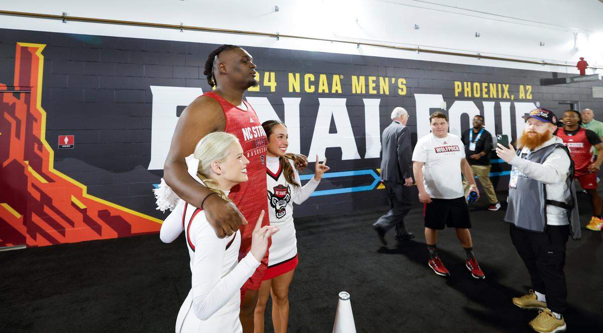 N.C. State’s DJ Burns Jr. (30) poses with cheerleaders after during the Wolfpack’s practice at State Farm Stadium in Glendale, Ariz., Friday, April 5, 2024. The Wolfpack will face Purdue in the NCAA Tournament national semifinals Saturday.