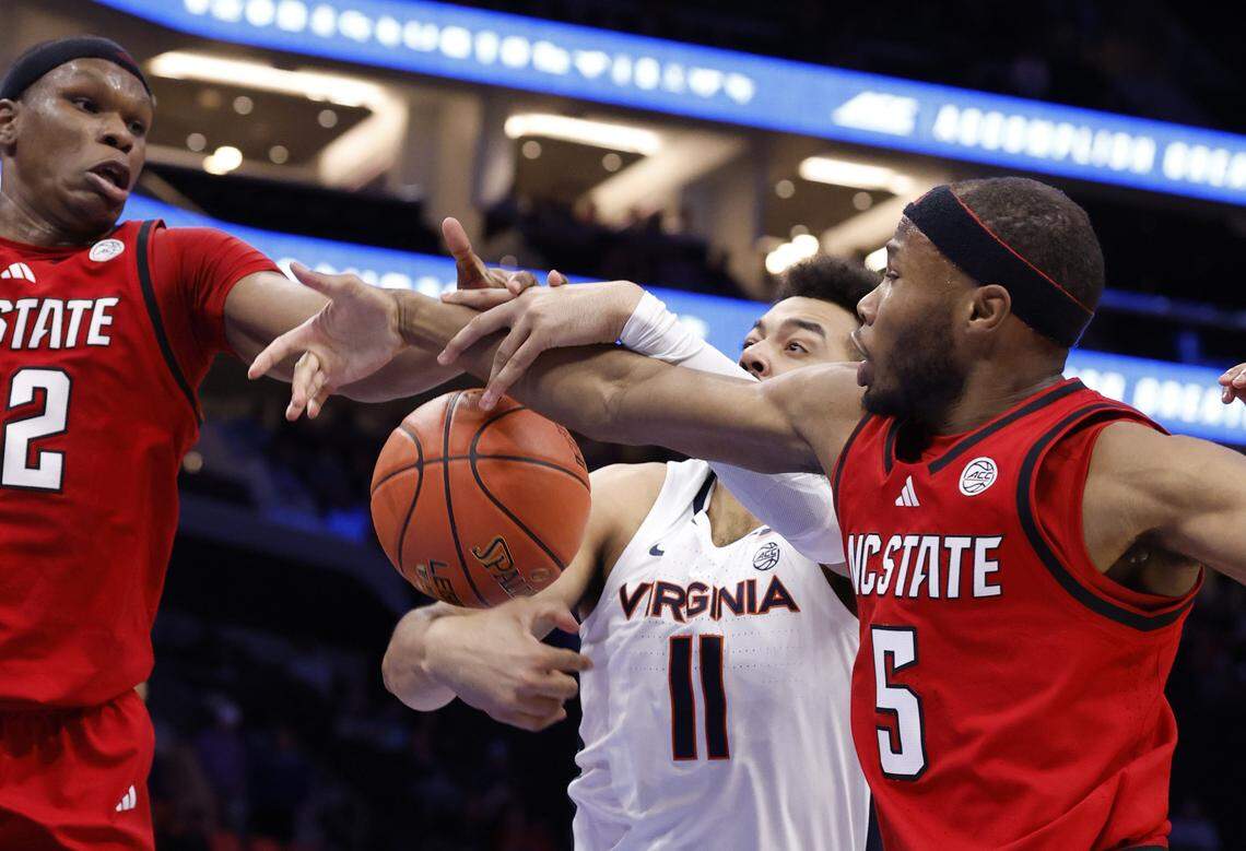 N.C. State's Tre Holloman (5) and Ven-Allen Lubin (22) defend Virginia's Devin Tillis (11) during the first half of N.C. State’s game against Virginia in the quarterfinals of the 2026 ACC Men’s Basketball Tournament at the Spectrum Center in Charlotte, N.C., Thursday, March 12, 2026.