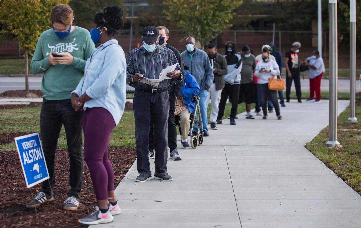 Voters wait in line at the Durham County Main Library on the morning of the first day of early voting in Durham, N.C., Thursday, Oct. 15, 2020.
