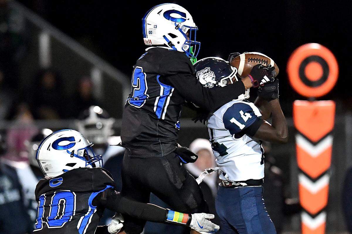 Southeast Raleigh wide receiver Cam Bullock (14) makes  the catch against Clayton's Akedran Crumel (13) during the second half. The Clayton Comets and the Southeast Raleigh Bulldogs met in the fourth round of the NCHSAA 7A Playoffs in Clayton, N.C. on November 28, 2025.