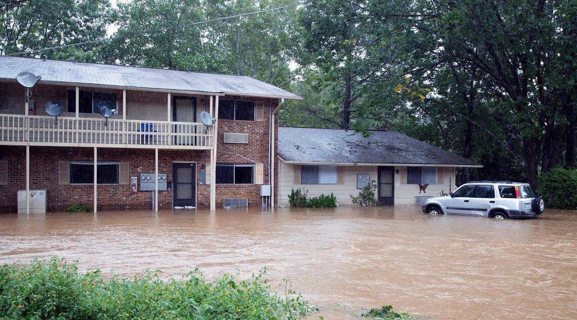 Flood waters begin to go down in the parking lot of Camelot Village Condominiums on South Estes Drive in Chapel Hill. The dark shadow on the brick building shows where the water was at its highest level.
