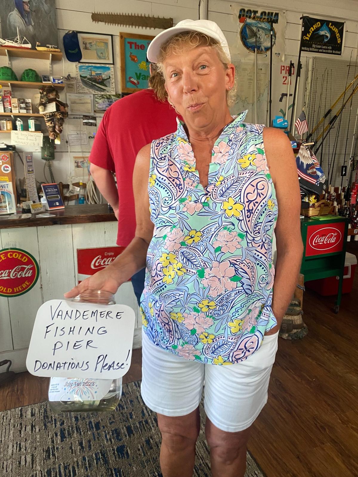 Debbie Hudson, who owns Squidders Bait & Tackle with her husband Russ, shows off the tip jar she hopes will one day fund a fishing pier for their tiny coastal town.