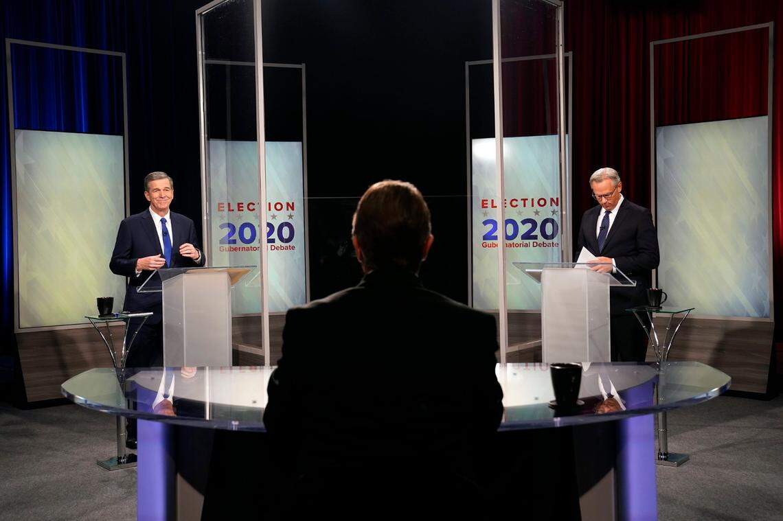 North Carolina Gov. Roy Cooper, left, and Lt. Gov. Dan Forest participate in a live televised debate moderated by Wes Goforth, center, at UNC-TV studios in Research Triangle Park, N.C., Wednesday, Oct. 14, 2020.