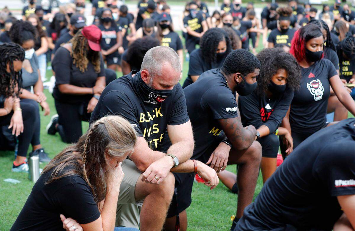 N.C. State football coach Dave Doeren along with other Wolfpack athletes, coaches and staff kneel for 8:46, the time police kneeled on George Floyd, during a #PackUnited peaceful protest against racial and social injustice outside Holladay Hall on the campus of N.C. State Saturday, Sept. 12, 2020.