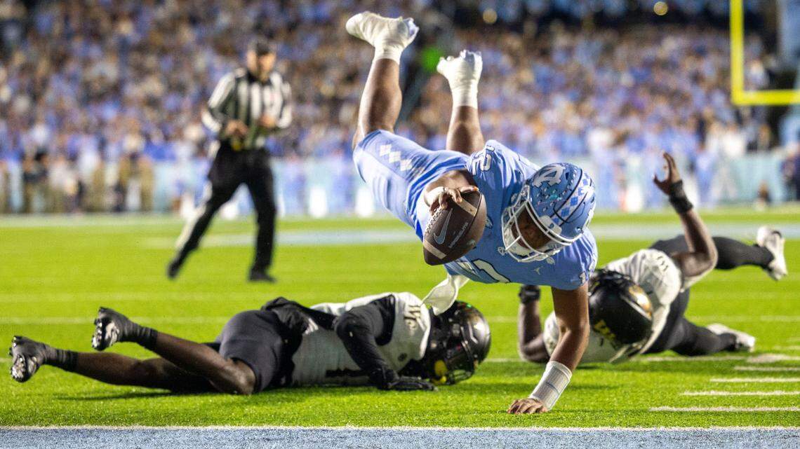 North Carolina quarterback Jacolby Criswell (12) dives over Wake Forest defensive back Zamari Stevenson (17) to score on a 4-yard run to give the Tar Heels a 7-3 lead in the second quarter on Saturday, November 16, 2024 at Kenan Stadium in Chapel Hill, N.C.