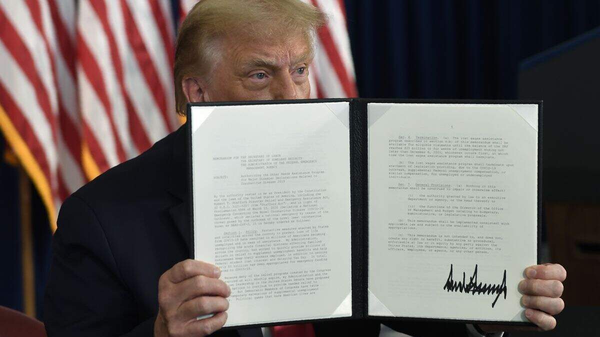 President Donald Trump signs an executive order during a news conference at the Trump National Golf Club in Bedminster, N.J., Saturday, Aug. 8, 2020. (AP Photo/Susan Walsh)