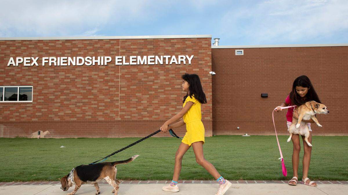 kMaya Glover, 7, and Zoe Glover, 11, walk with their dogs, Cinnamon and Flower, prior to the first day of the school year at Apex Friendship Elementary School on Monday, Aug. 29, 2022, in Apex, N.C.