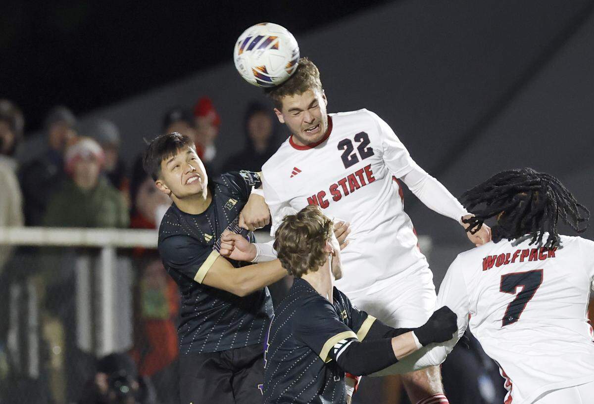 N.C. State's Drew Lovelace (22) heads the ball over Washington's Gabe Fernandez (44) during Washington’s 3-2 overtime victory over N.C. State in the 2025 Men’s Soccer National Championship at WakeMed Soccer Park in Cary, N.C., Monday, Dec. 15, 2025.