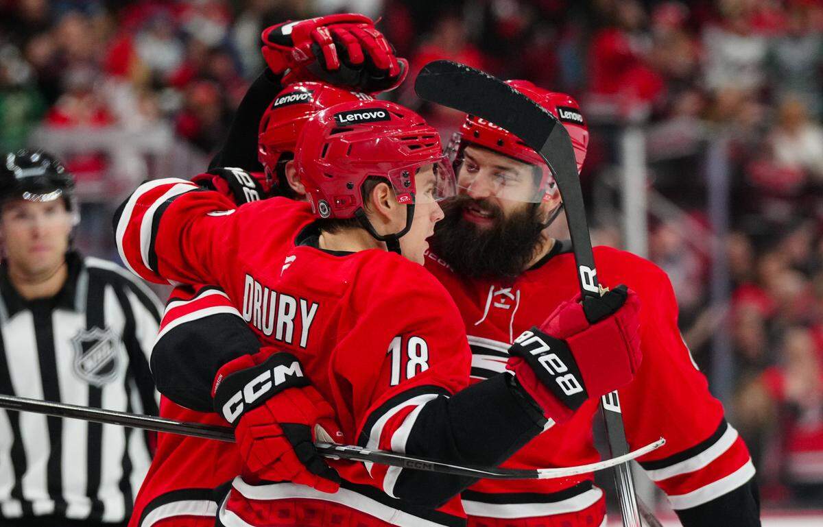 Carolina Hurricanes left wing Eric Robinson (50) is congratulated by center Jack Drury (18) defenseman Brent Burns (8) after his goal against the Colorado Avalanche during the first period at Lenovo Center.