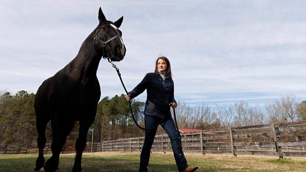 Olivia Turner walks with Klinger, a retired military working equine, at a farm in Zebulon, N.C. on Wednesday, Dec. 13, 2023. Turner adopted Klinger, a horse formerly with the Army caisson platoon, in November.
