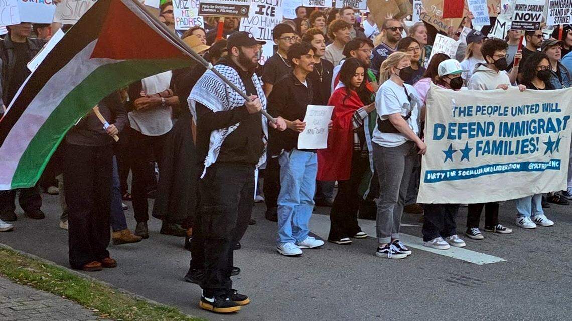 Protesters hold signs during a march in downtown Raleigh on Sunday denouncing a federal immigration operation underway in Charlotte.