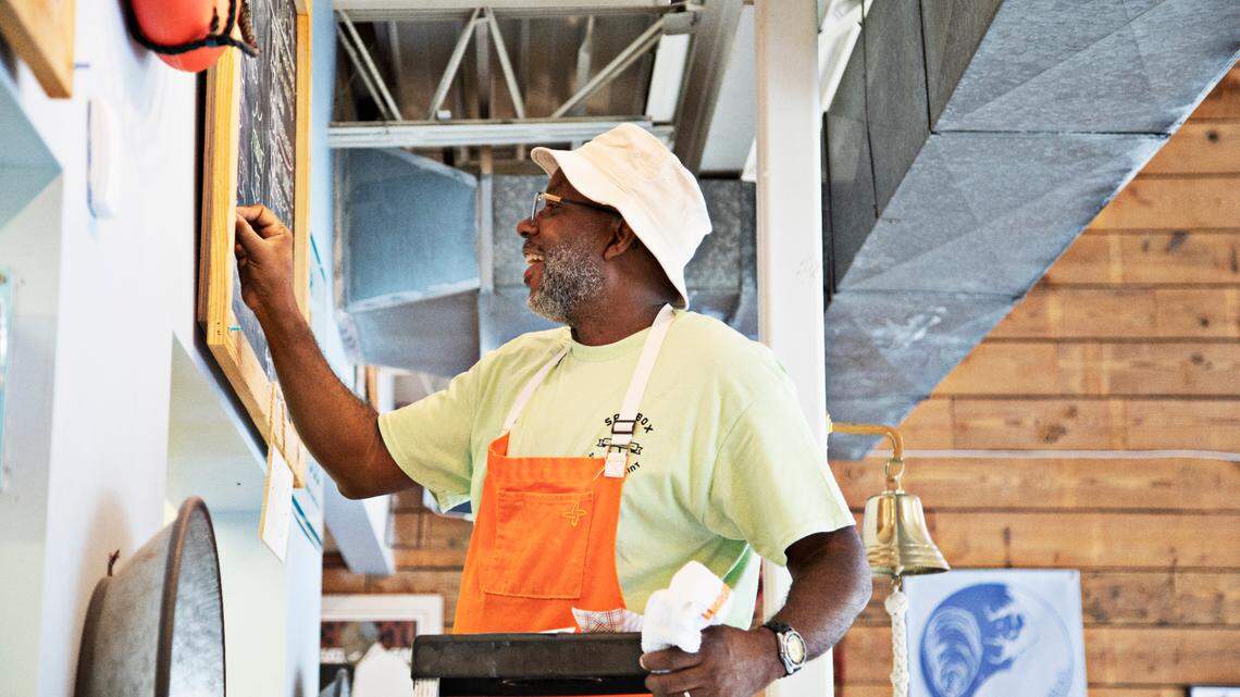Chef Ricky Moore writes the days menu on the chalkboards before lunch service on June 15, 2022 at his Durham restaurant, Saltbox Seafood Joint. “After all of these years, I’ve never had paper menus,” says Moore, who on June 13, 2022 was named Best Chef: Southeast by the James Beard Foundation.