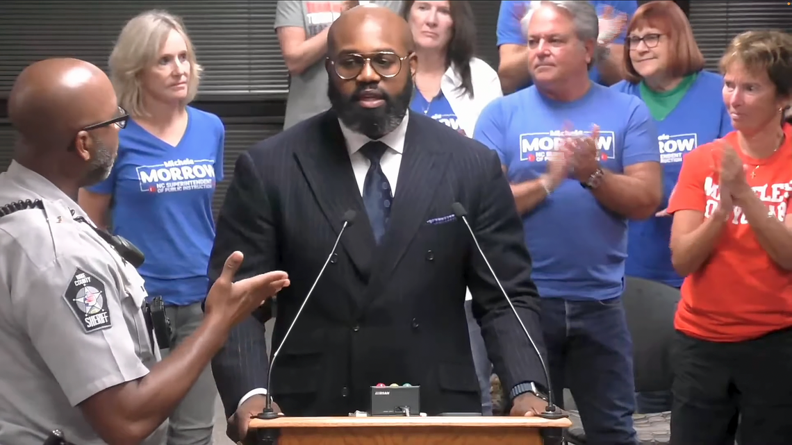 Wake County pastor John Amanchukwu is asked to leave by sheriff’s deputy during the public comment section of a Wake County school board meeting Oct. 1, 2024. Amanchukwu would ultimately be escorted from the meeting in handcuffs after refusing to leave the podium.