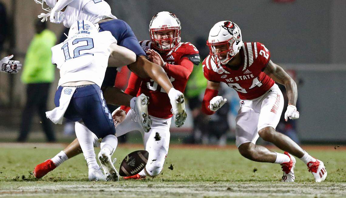 N.C. State place kicker Christopher Dunn (32) heads to pull in his on-sides kick late in the second half of N.C. State’s 34-30 victory over UNC at Carter-Finley Stadium in Raleigh, N.C., Friday, November 26, 2021. North Carolina’s Stephen Gosnell (12) is to the left and N.C. State’s Derrek Pitts Jr. (24) is to the right.
