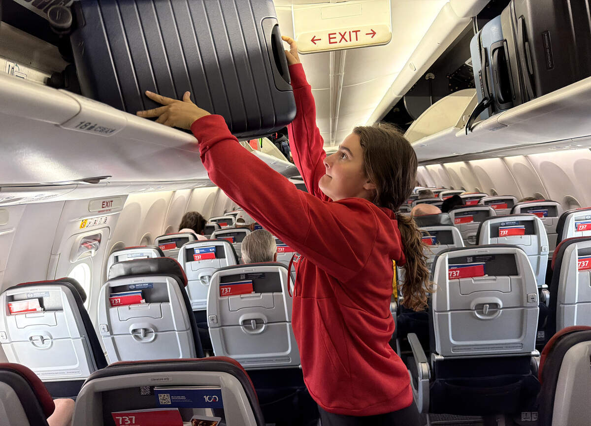 Charlotte Jackson places her luggage in the overhead compartment on her fight to Las Vegas from Phoenix Saturday, June 13, 2026. Jackson, her father, boyfriend and friend all departed from Raleigh early Saturday morning in order to get to Las Vegas to watch the Canes play the Golden Knights in game six of the Stanley Cup Final Sunday.