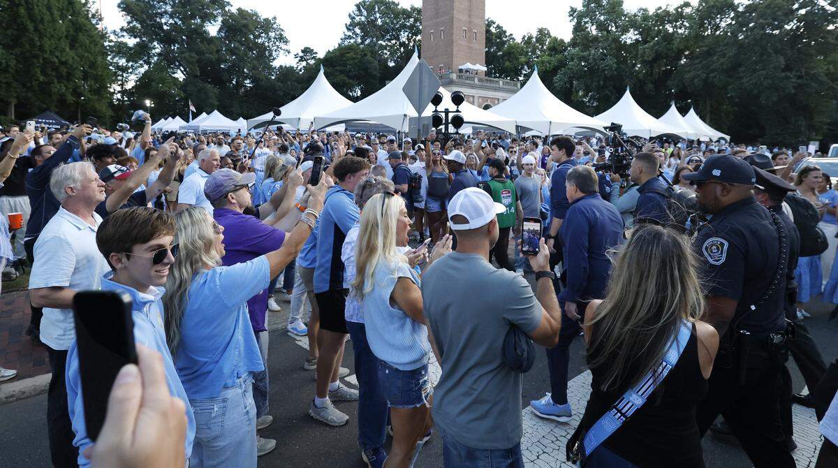 Fans cheer North Carolina head coach Bill Belichick as he and the team walk towards Kenan Stadium during the Old Well Walk before UNC’s game against TCU in Chapel Hill, N.C., Monday, Sept. 1, 2025.