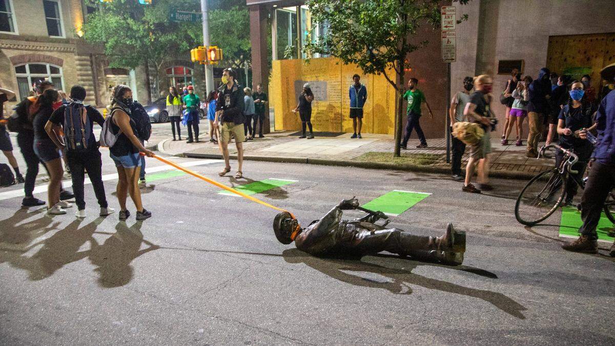 Protesters drag a figure pulled from the Confederate monument at the State Capitol down Salisbury Street in Raleigh on Juneteenth, Friday, June 19, 2020.