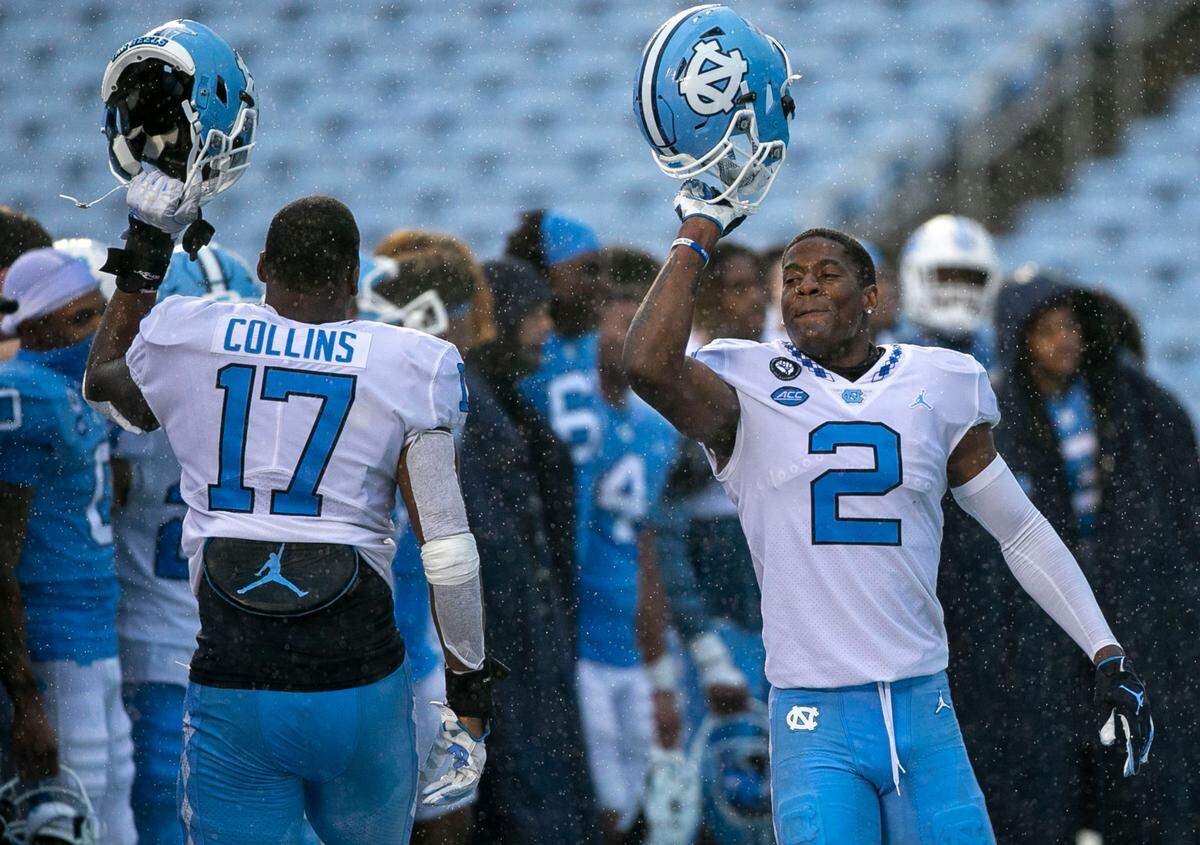 North Carolina’s Don Chapman (20) and teammate Chris Collins (17) celebrate in the rain as the band plays the Alma Mater at the conclusion of the Tar Heels’ Spring football game on Saturday, April 24, 2021 in Chapel Hill, N.C.