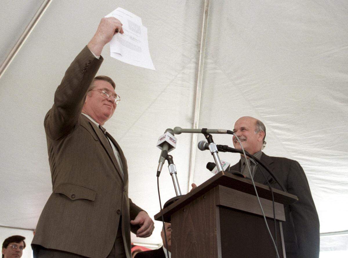 Steve Stroud of the Centennial Authority holds up a document of intent after he and Hartford Whalers owner Peter Karmanos (right) signed it at festivities celebrating the announcement in 1997