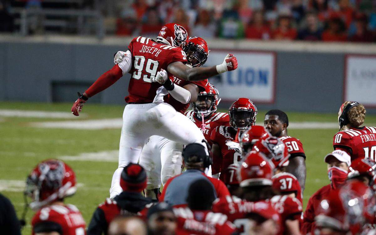 N.C. State defensive lineman Daniel Joseph (99) celebrates with linebacker Isaiah Moore (1) after Moore forced a safety during the second half of N.C. State’s 15-14 victory over Liberty at Carter-Finley Stadium in Raleigh, N.C., Saturday, Nov. 21, 2020.