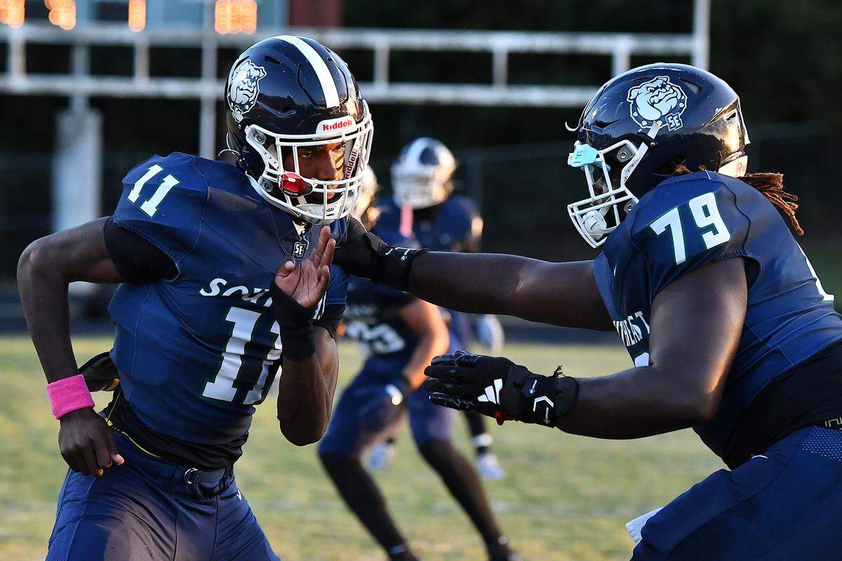 Southeast Raleigh defensive end Keysaun Eleazer (11) works with defensive lineman Grayson Williams (79) during pregame drills before their game with Clayton. The Southeast Raleigh Bulldogs and the Clayton Comets met in a non-conference football game in Raleigh, N.C. October 3, 2025