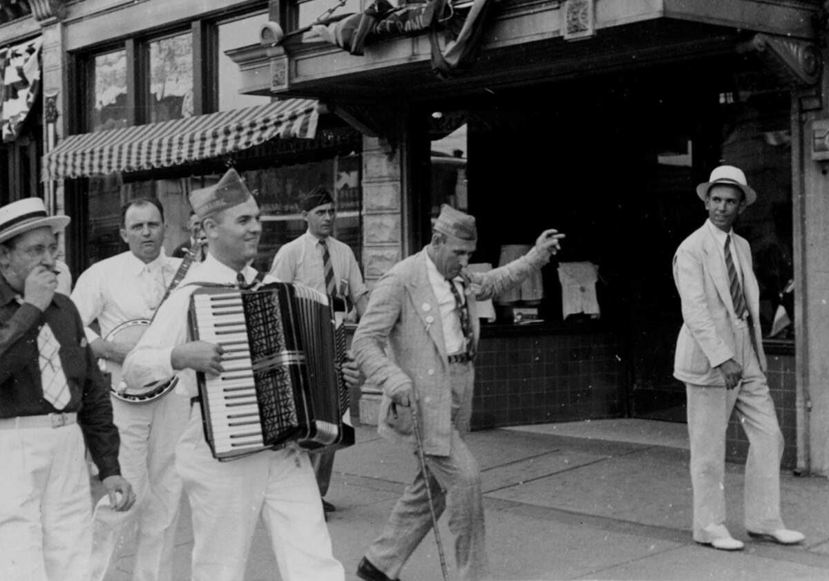 Members of the American Legion Second Line Band including American Legion Second Line Band one with banjo, another with an accordion and the leader dancing with a cane in Raleigh’s American Legion parade in 1939.