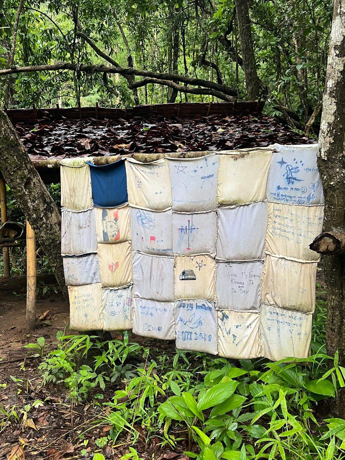 A memorial for loved ones killed by the Burma Military inside Karenni State, Burma, hangs at the Jungle Discipleship School. The cloth hangs from bamboo and contains written memorials of lost loved ones. Yates spoke with these civilians and soldiers to tell the stories of how their loved ones were killed.