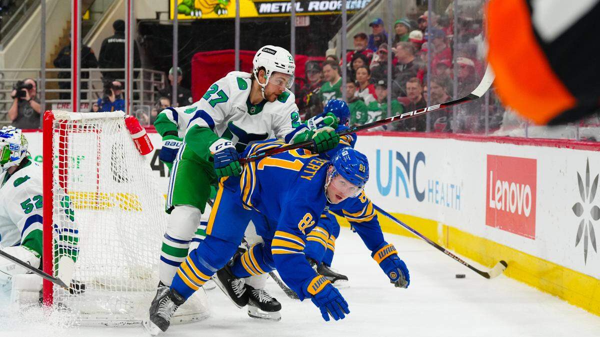 Carolina Hurricanes center Tyson Jost (27) cross checks Buffalo Sabres center Sam Lafferty (81) during the second period at Lenovo Center.