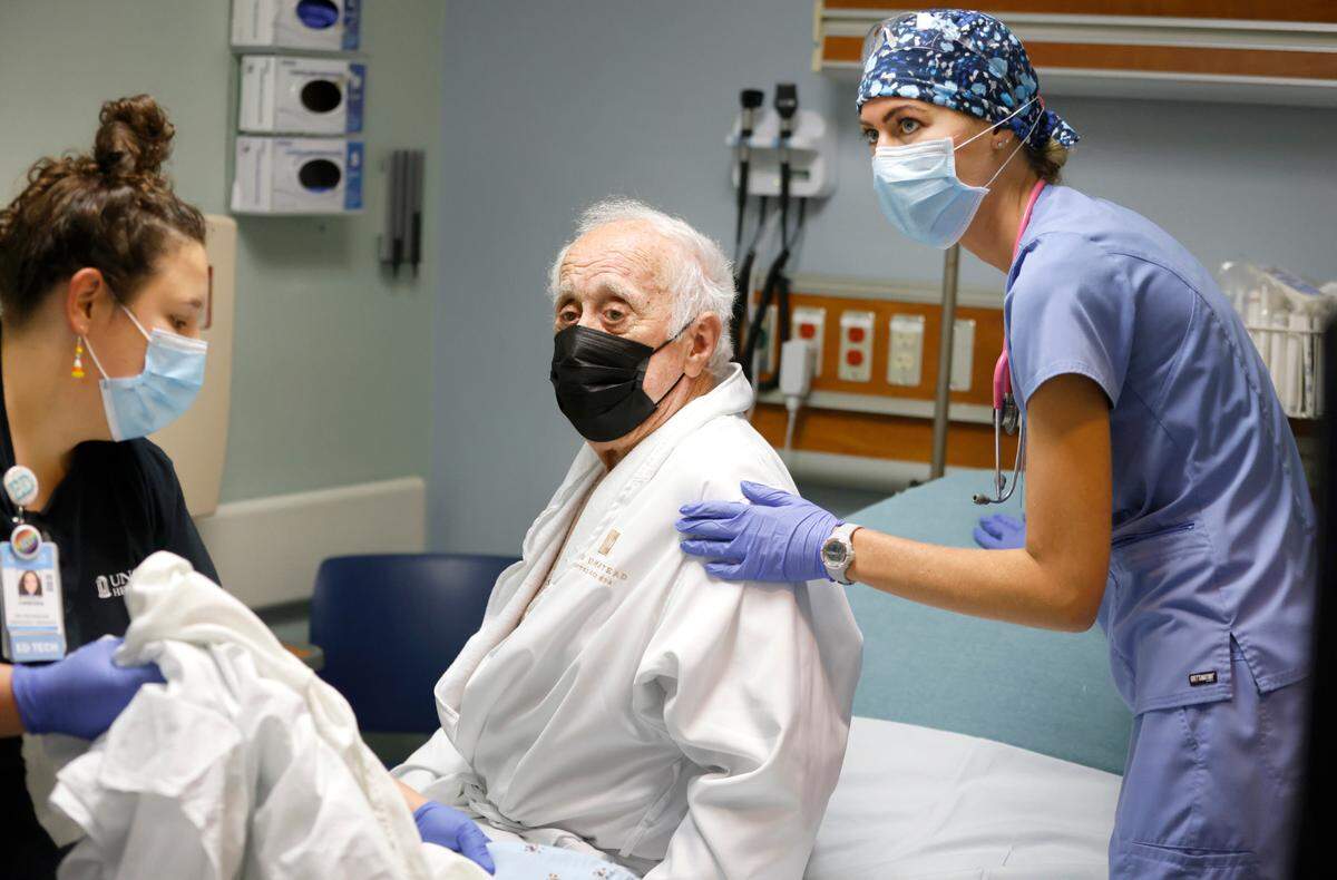 Erica South, right, and Vanessa Fontana help John Nuhn get into bed in the emergency department at UNC REX Hospital in Raleigh, N.C., Friday, October 1, 2021.