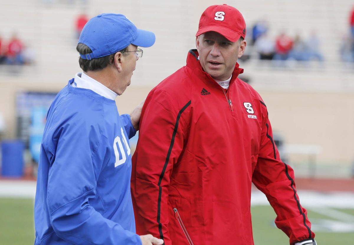 In this 2013 file photo, Duke’s David Cutcliffe, left, talks with N.C. State’s Dave Doeren before the Blue Devils’ game against the Wolfpack at Wallace Wade Stadium in Durham, N.C., Saturday, November 9, 2013. 