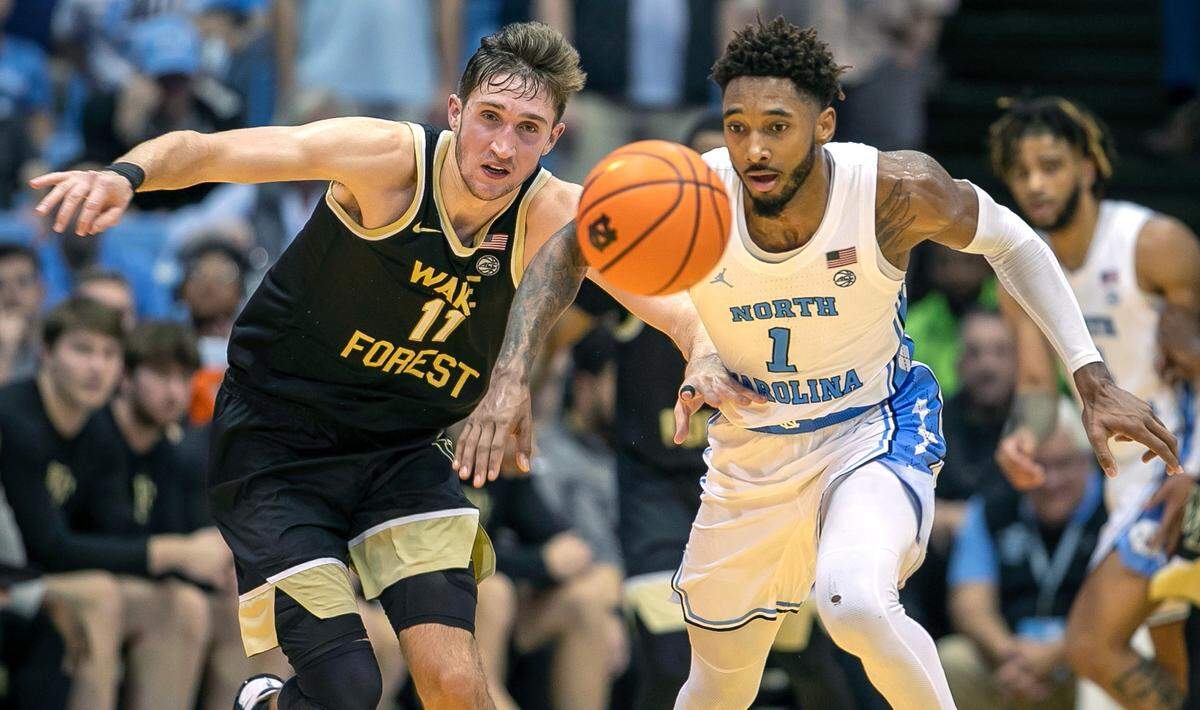 Wake’s Andrew Carr (11) and North Carolina’s Leaky Black (1) chase down a loose ball on Wednesday, January 4, 2023 at the Smith Center in Chapel Hill, N.C.