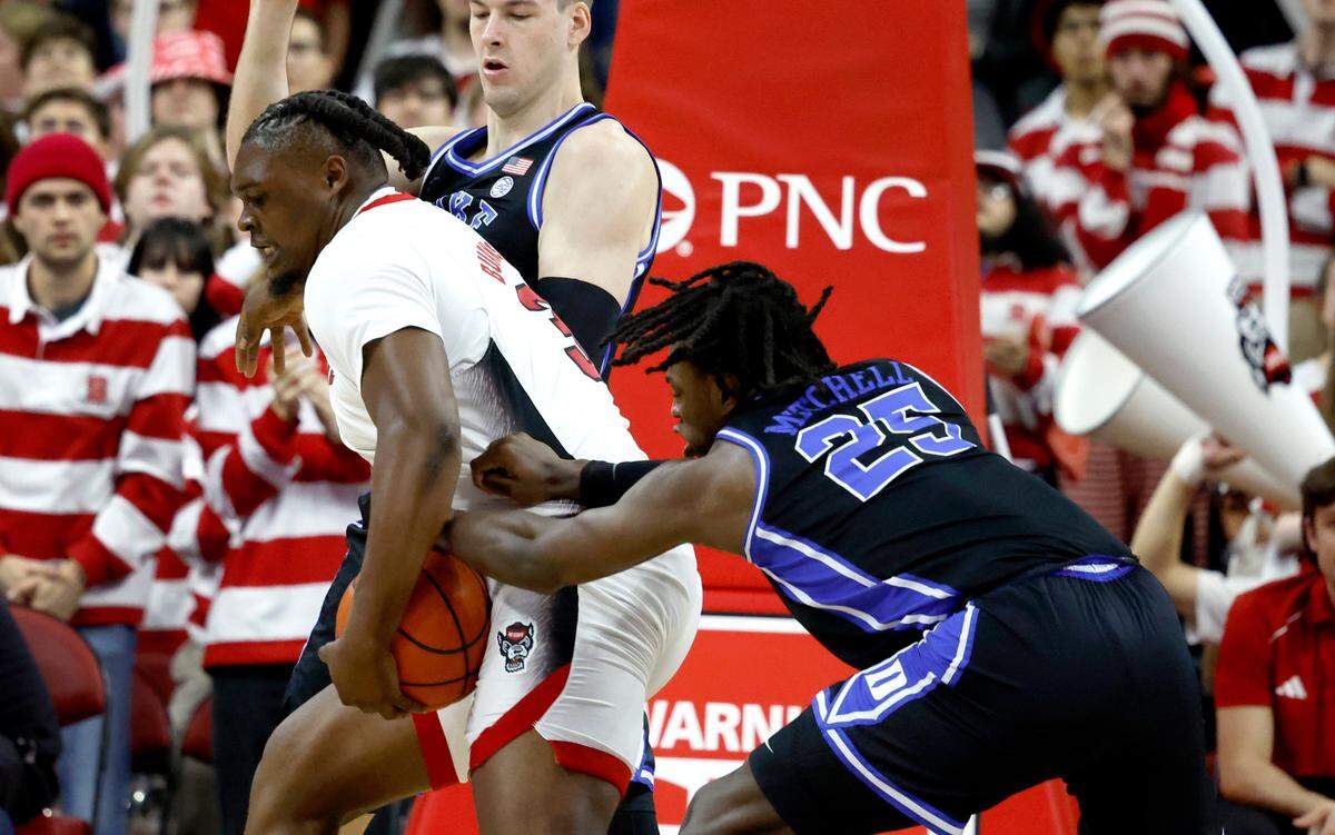 N.C. State’s DJ Burns Jr. (30) drives by Duke’s Kyle Filipowski (30) and Mark Mitchell (25) during the first half of N.C. State’s game against Duke at PNC Arena in Raleigh, N.C., Monday, March 4, 2024.