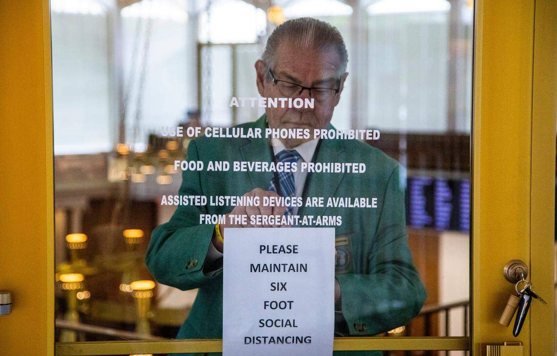 Sgt. at Arms Garland Shepherd tapes a sign at an entrance of the House gallery at the Legislative Building Monday, May 18, 2020.