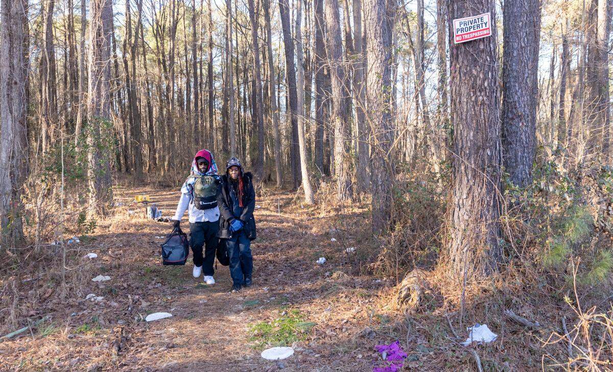 A man who calls himself “Wiz,” left, and a woman who identified herself as “Sesame” exit the woods where they they live in a tent next to the exit ramp from eastbound I-40 onto South Saunders Street in Raleigh.