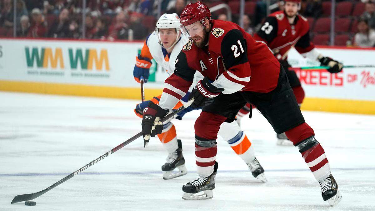Arizona Coyotes center Derek Stepan (21) skates past New York Islanders Anthony Beauvillier (18) during an NHL hockey game Feb. 17, 2020, in Glendale, Ariz. (AP Photo/Rick Scuteri)