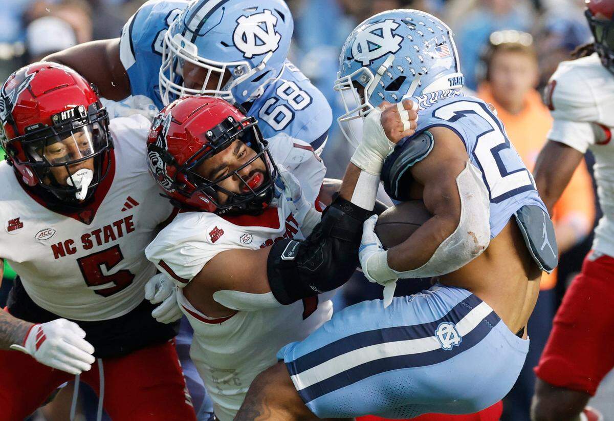 N.C. State defensive end Davin Vann (1) tackles North Carolina running back Omarion Hampton during the first half of N.C. State’s game against UNC at Kenan Stadium in Chapel Hill, N.C., Saturday, Nov. 30, 2024.