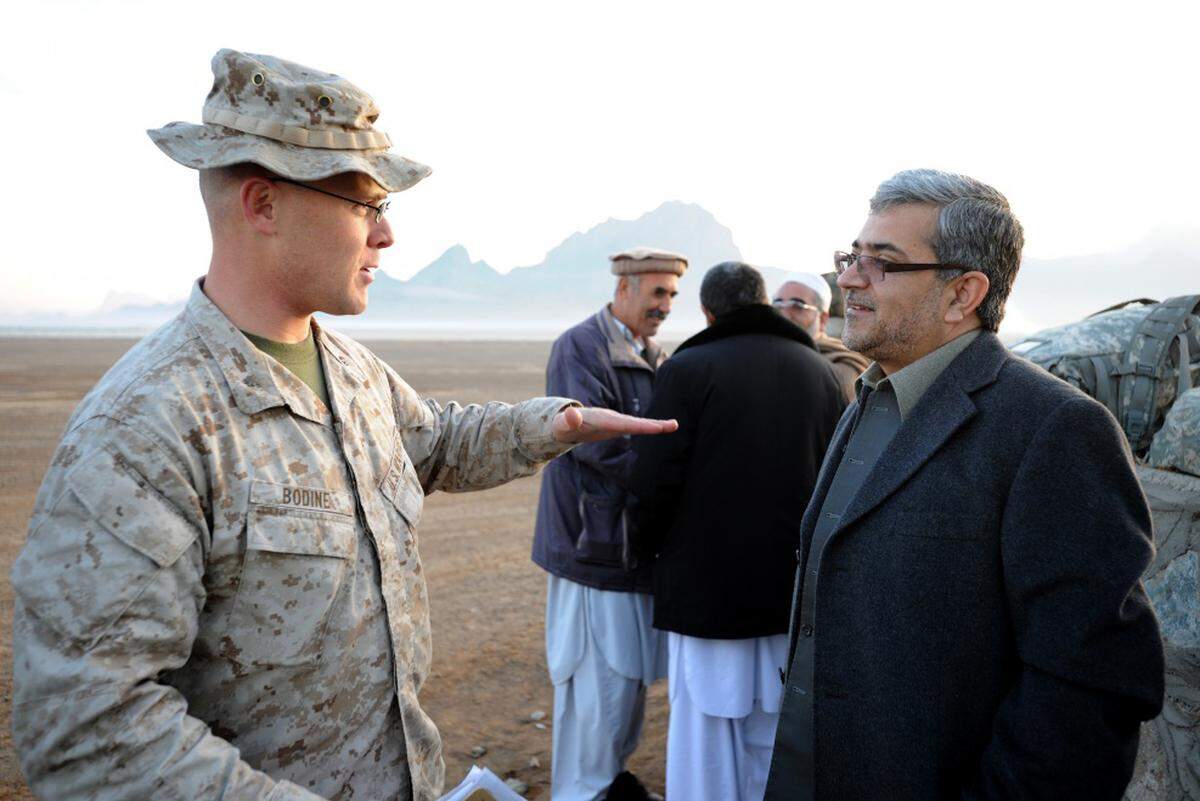In this 2010 photo, then U.S. Marine Corps Maj. Wayne Bodine talks with in Farah province, Afghanistan with Farah province Gov. Rahool Amin about the capabilities of the Marine V-22 Osprey tilt rotor aircraft.