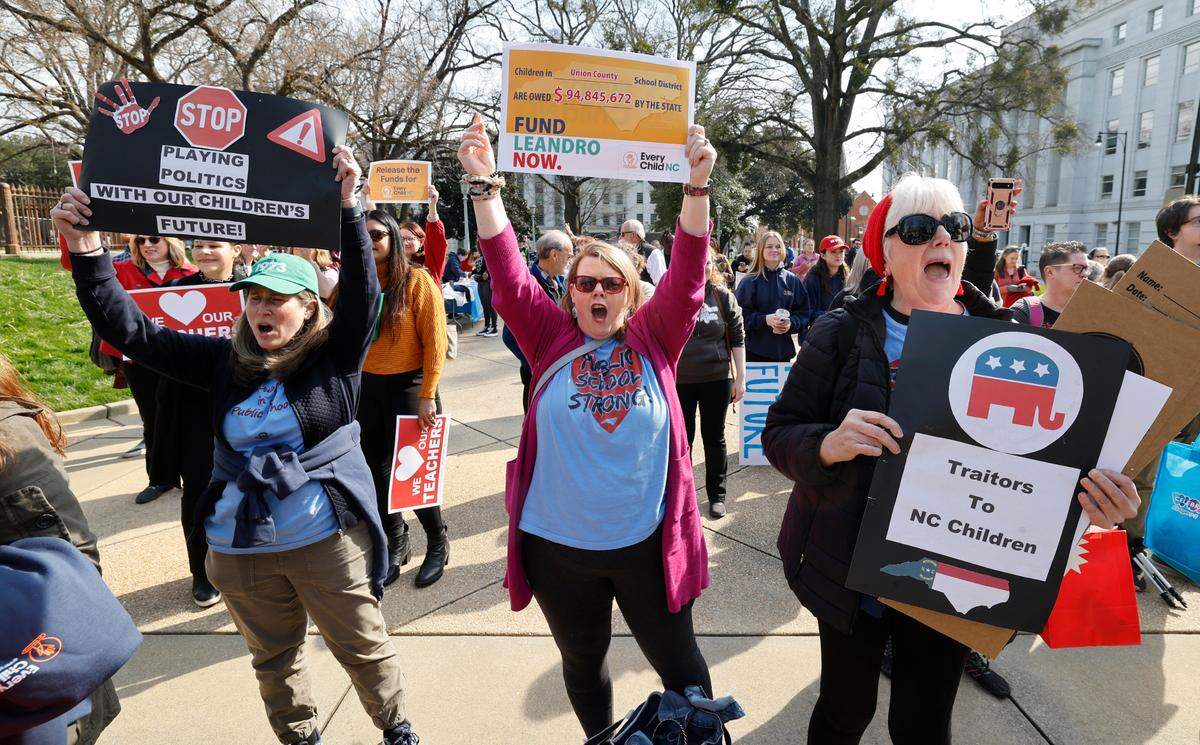From left, Sara Juhl from Weddington, Jen Sanders from Waxhaw and Meg Bell from Monroe cheer on speakers during a rally for education funding on the grounds of the N.C. State Capitol in Raleigh on Thursday, Feb. 22, 2024. The rally happened as the state Supreme Court heard oral arguments in the long-running Leandro school funding case.