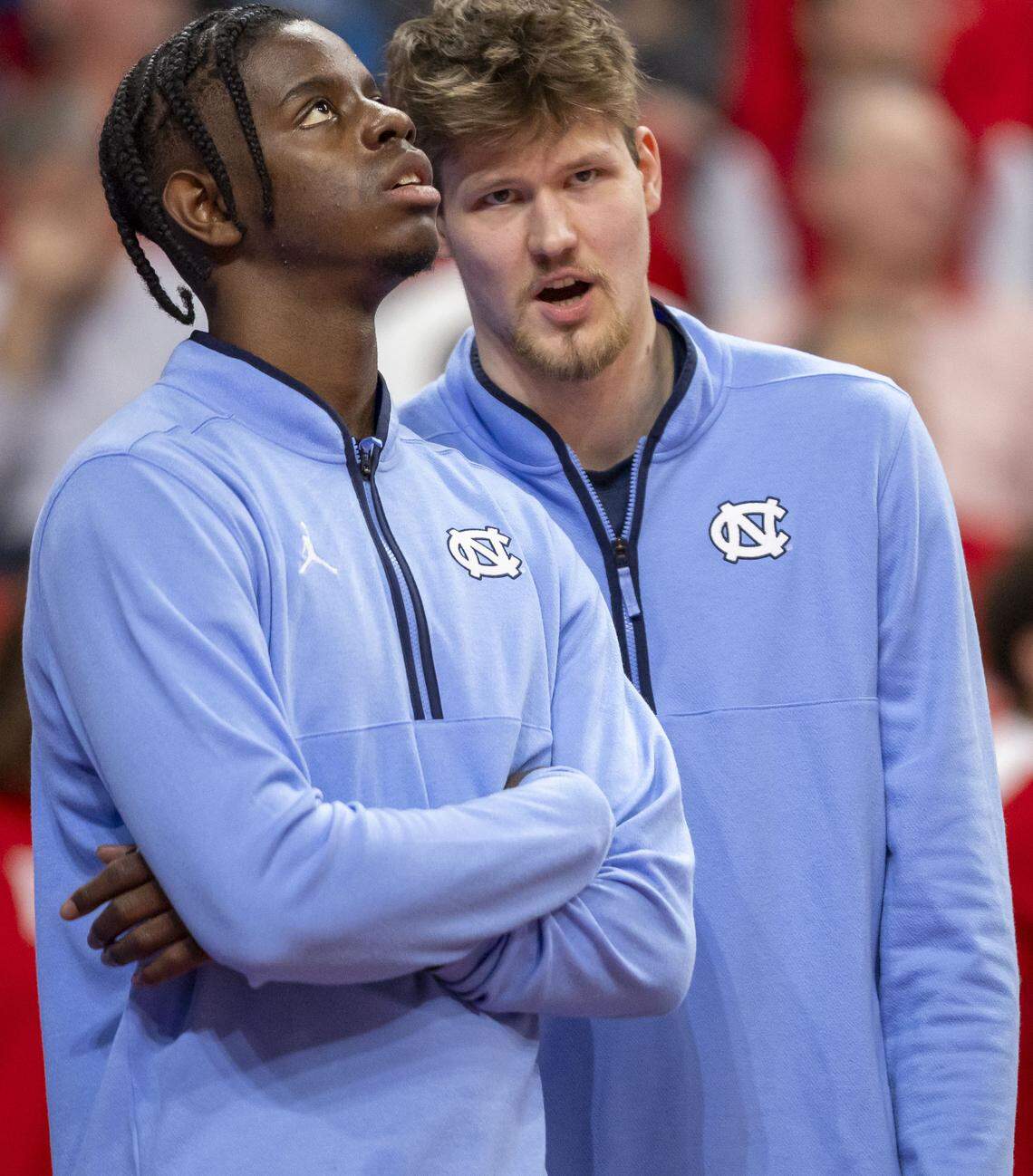 North Carolina forward Caleb Wilson, out with a fractured left hand, checks the score, as he listens to center Henri Veesaar (13), also out with an injury, in the second half against N.C. State on Tuesday, February 17, 2026 at Lenovo Center in Raleigh, N.C.