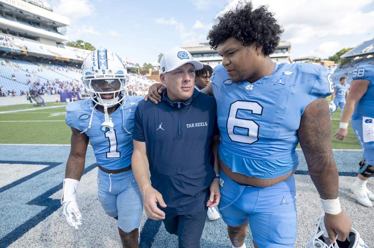 North Carolina defensive coordinator Geoff Collins is embraced by defensive lineman Joshua Harris (6) as they leave the field following the Tar Heels’ 70-50 loss to James Madison on Saturday, September 21, 2024 at Kenan Stadium in Chapel Hill, N.C.