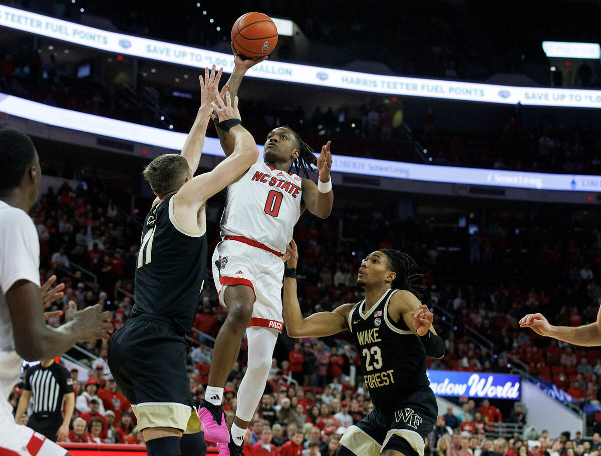 N.C. State’s DJ Horne drives to the basket past Wake Forest’s Andrew Carr and Hunter Sallis during the second half of the Wolfpack’s 83-76 win at PNC Arena on Tuesday, Jan. 16, 2024, in Raleigh, N.C.