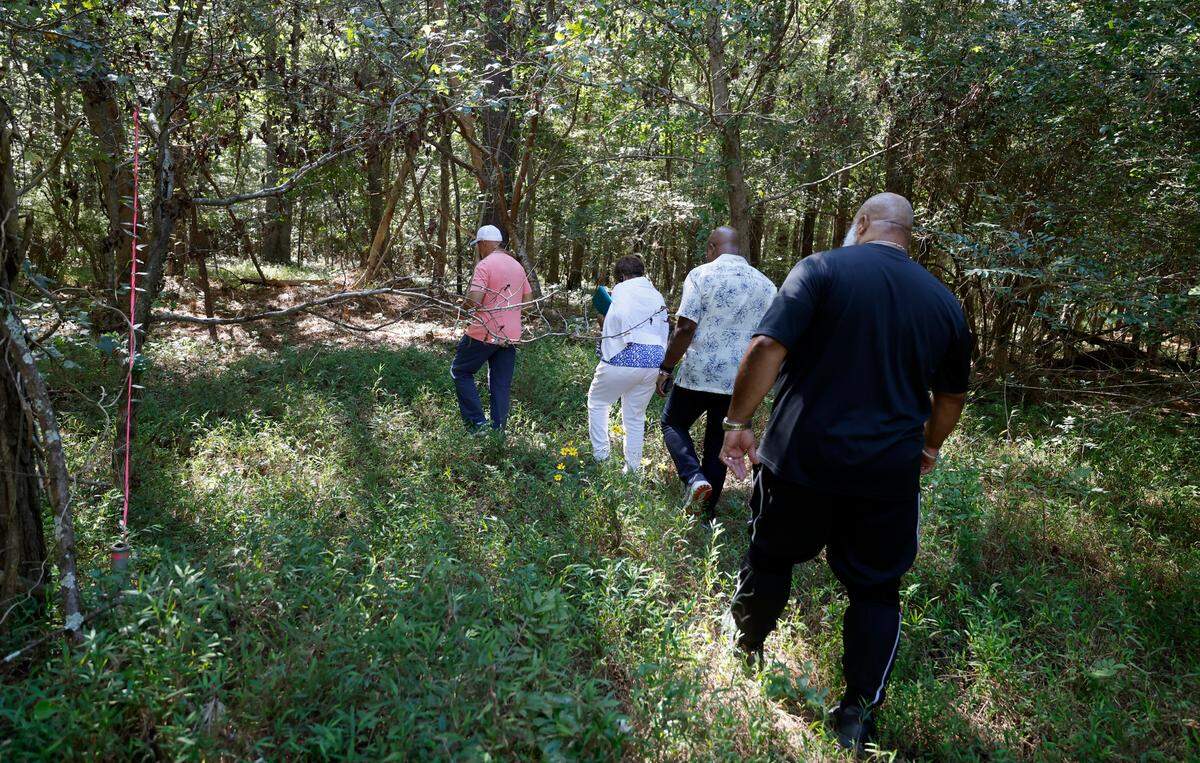 From left Larry Harris, Valerie Frasier, Glenn Evans and Donald Evans, Sr. walk through the woods on Friday, Sept. 15, 2023, to get to Byrd Chapel Cemetery off New Elam Church Rd. in Moncure, N.C.